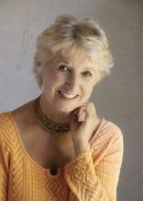 A photo of Barbara Lounsberry, a woman with short blonde hair, and a yellow sweater. 