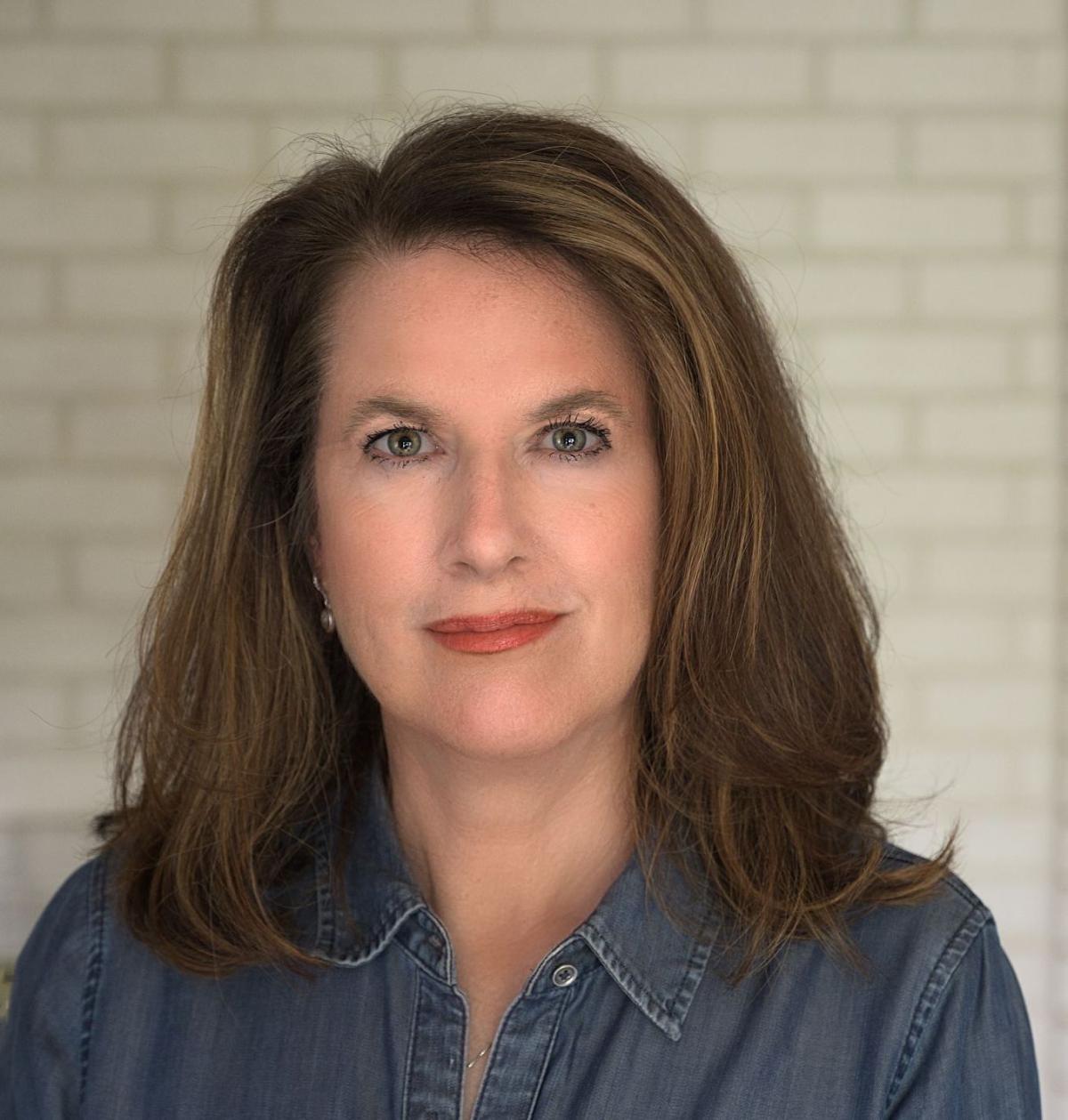 A photo of Wini Moranville, a woman with long brown hair and a denim collared shirt. 